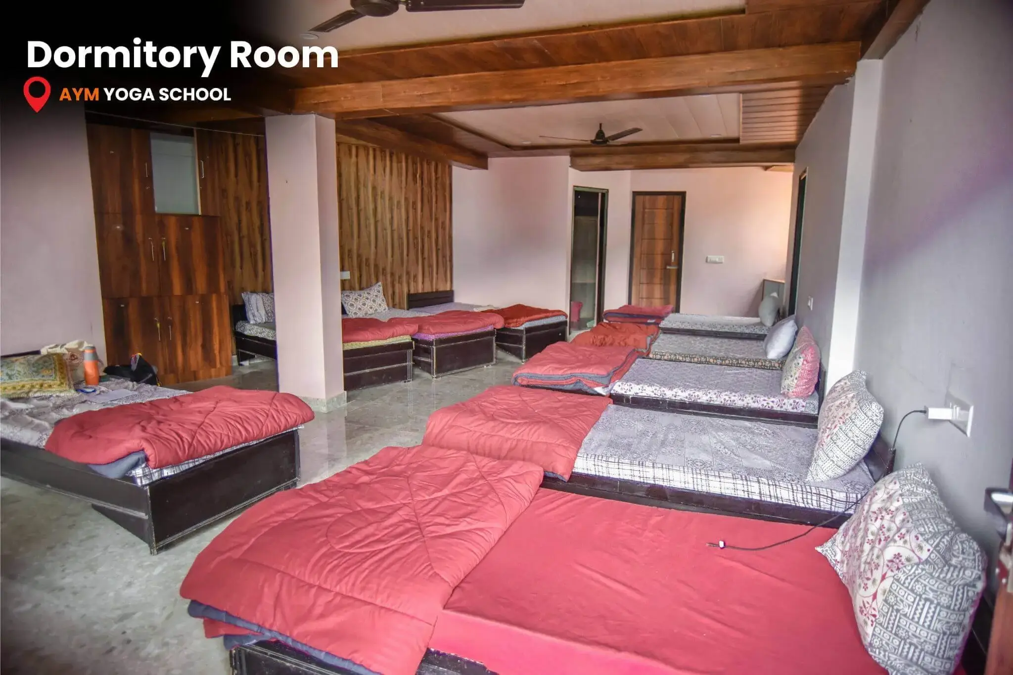 Male dormitory room with multiple beds and lockers for yoga students at AYM School
